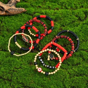 Detail of Game Day elastic bracelets with Heishi beads and football charms on green moss