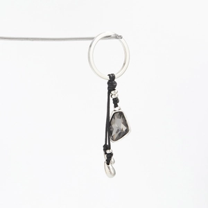 Detail of a minimalist bag charm with faceted acrylic crystal and silver metal ring