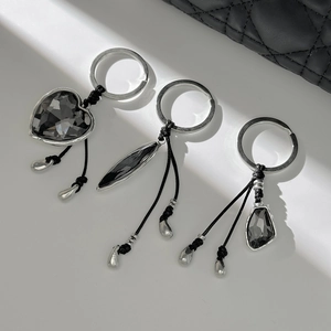Three faceted dark crystal pendants with silver metal rings on a quilted leather bag