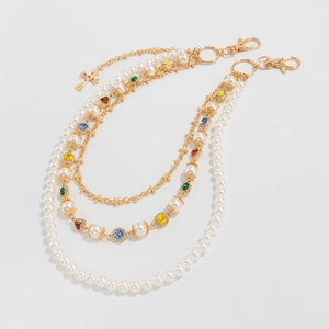Detail of layered gold hip-hop waist chain with pearls, colorful gems and cross pendant