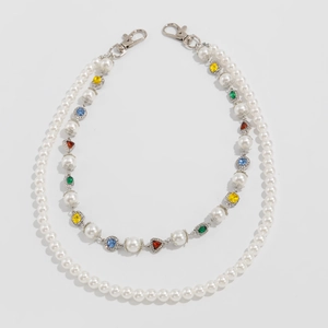 Macro detail of multilayer waist chain with white pearls and colorful gemstone charms