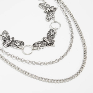 Macro detail of gothic layered silver chain belt featuring skull butterfly charms