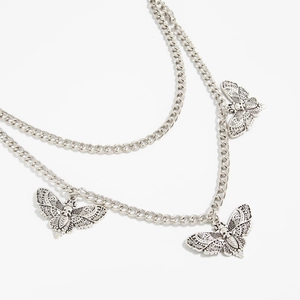 Detail of gothic moth and skull charms on multi-layer silver pants chain with tassel