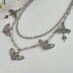 Detail of silver double-layered gothic necklace with skull butterfly and cross pendants