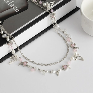 Detail van zilveren dubbellaagse tailleketting met strikjes en roze imitatieparels