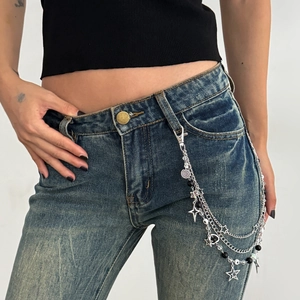 Detail van zilveren gelaagde broekketting met sterren en kralen op blauwe spijkerbroek