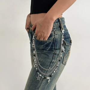 Detail van meerlaagse zilveren broekketting met sterhangers op vintage denim jeans