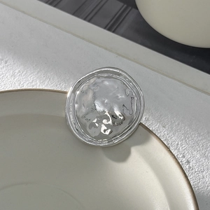 Vue détaillée d'une broche argentée avec texture de lave sur fond blanc minimaliste