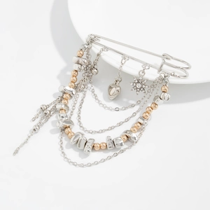 Detail of silver safety pin brooch with metallic tassels, gold beads, and heart pendant