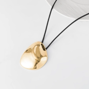 Vista detallada de colgante de gota dorada brillante con cordón negro de estilo moderno