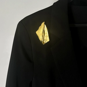 Gros plan détaillé d'une broche froissée dorée irrégulière sur un revers de costume noir