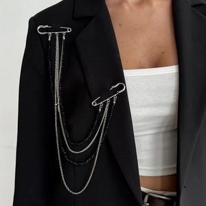 Detail of punk style silver chain brooch with star pins on black suit jacket