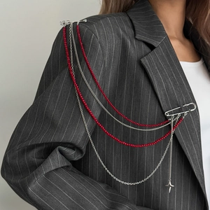 Detail of silver tassel chain brooch with red beads and star pendant on suit