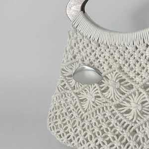 Détail du sac en macramé montrant la texture tissée et la boucle ovale en métal