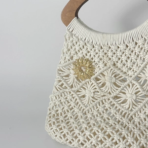 Détail de la broche soleil dorée sur un sac en macramé blanc fait main avec anses en bois