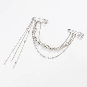 Macro detail of punk style silver tassel chains and double safety pin suit brooches