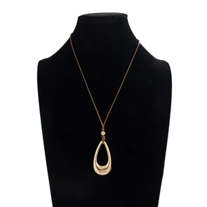 Primer plano de un gran colgante de gota de oro pulido en un collar de cordón marrón oscuro