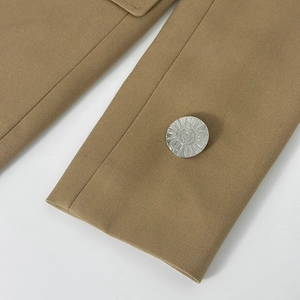 Vue détaillée d'un bouton en métal argenté en relief sur un tissu de blazer texturé