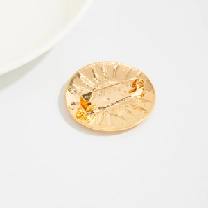 Détail de l'épingle de fermeture et de la texture martelée de la broche dorée ronde