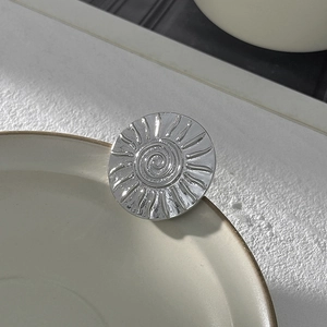 Détail macro d'une broche en métal argenté irrégulier avec texture spirale gaufrée