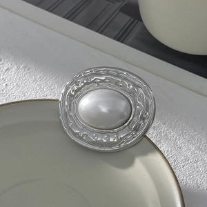 Vue détaillée d'une broche en métal irrégulier avec texture martelée et perle