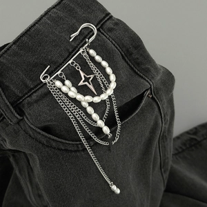 Detail of silver safety pin brooch with pearl fringe and star charm on denim fabric