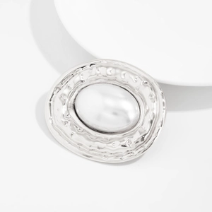 Vue détaillée d'une broche ovale argentée à texture martelée avec incrustation de perles