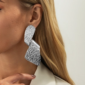 Zilveren vloeibare metalen druppeloorbellen met gehamerde textuur op blond model