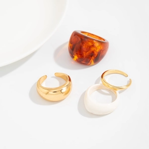 Detailed shot of amber resin and gold metal stacking rings set on a white surface