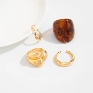 Detail of four-piece ring set with golden fluid metal bands and amber resin ring