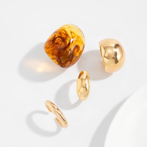 Macro detail of amber resin ring and polished gold metal rings on white ceramic plate