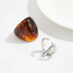 Detail of amber resin ring with triangular cutting and adjustable silver metal band