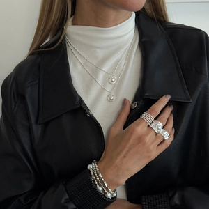 Detail einer silbernen Halskette mit Perlenanhänger und passenden Ringen am Modell