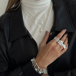 Silberne mehrlagige Perlenkette mit passenden Ringen und Armband an einem Frauenmodel