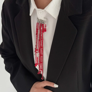 Macro shot of red beaded fringe brooch with silver chains on a black blazer jacket