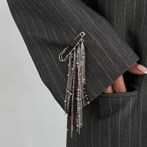 Detail of silver tassel brooch with dark crystal beads pinned on a grey striped suit sleeve