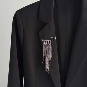 Detail of silver brooch with cascading tassel chains and deep red crystal beads on a suit