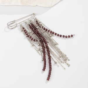 Detailed view of silver safety pin brooch with long layered chains and purple crystal beads