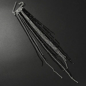 Detail of silver safety pin brooch featuring cascading black crystal beaded fringe chains