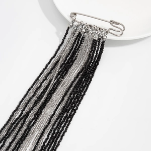 Detailed view of multilayer beaded fringe brooch with black and gray crystal tassels