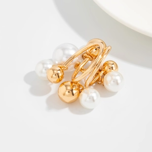 Detailed view of modern gold intertwined rings with tiered pearls on a minimalist base