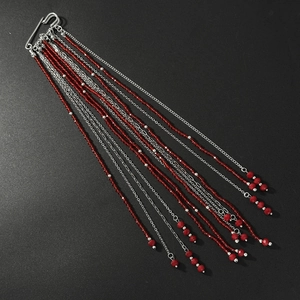 Macro shot of red beaded tassel chains with silver pins on a dark matte background