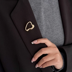 Close-up of golden irregular heart brooch with molten lava texture on a suit lapel