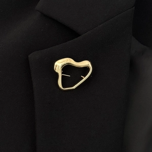 Irregular golden heart brooch on black suit blazer with polished lava metal texture