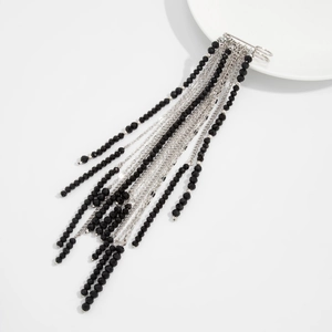 Detail showing long silver chain tassels and black crystal beads on a hip-hop style brooch