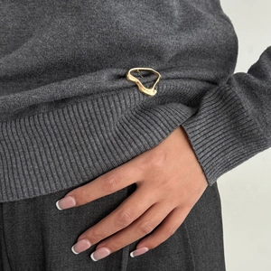 Irregular golden liquid lava metal brooch pinned on a grey knit garment as waist clip