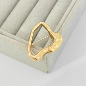 Golden liquid lava irregular brooch with mirror finish on velvet jewelry tray