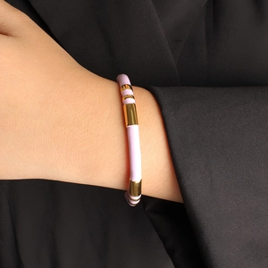 Detail of light purple enamel and gold stainless steel open bangle on a suit sleeve