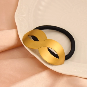 Macro view of gold 18k plated infinity charm on high elastic black ponytail hair tie