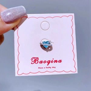 Nahaufnahme von herzförmigem blauen Zirkon Saturn Ohrring auf rosa Karte